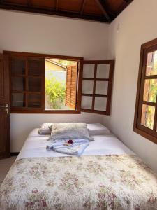 a bedroom with a bed with a blanket and a window at BEACH HOUSE pé na areia in Santa Cruz Cabrália