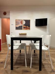 a dining room with a black table and white chairs at Almía apartment in Cinisi