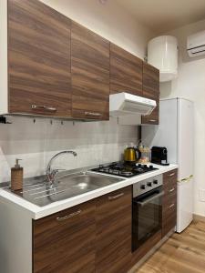 a kitchen with wooden cabinets and a stainless steel sink at Almía apartment in Cinisi
