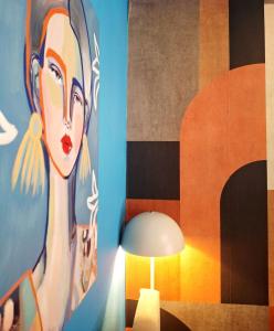 a painting of a woman on a wall next to a lamp at SuiteArtate in Patra