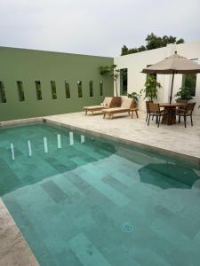 a swimming pool with chairs and a table and an umbrella at Hotel Boutique Casareyna in Puebla