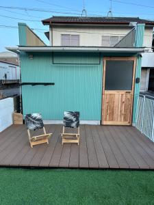 two chairs sitting on a deck in front of a house at Private Stay HANARE in Shishikui