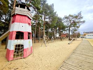 a playground with a red building in the sand at Bernsteinsee Home and Ferien Forest Chalet in Sassenburg +9 photos