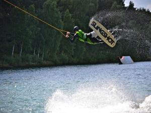 a man is in the air over a body of water at Bernsteinsee Home and Ferien Small Forest Chalet in Sassenburg