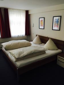 ein Schlafzimmer mit einem großen Bett mit weißer Bettwäsche und Kissen in der Unterkunft Brauereigasthof Krone Öhringen in Öhringen