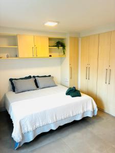 a bedroom with a large white bed and wooden cabinets at Camboflat in Niterói +43 photos