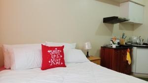 a white bed with a red pillow on it at B4B Staycation Avida Aspira in Cagayan de Oro