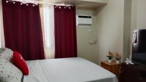 a bedroom with a bed and a red curtain at B4B Staycation Avida Aspira in Cagayan de Oro