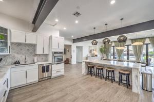a large kitchen with white cabinets and bar stools at CIELO - Modern Vegas Pool Oasis, Spa, Pickleball in Las Vegas