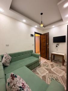 a living room with a green couch and a tv at فندق العجمي 100 in 6th Of October