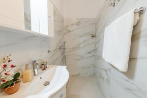 a white bathroom with marble walls and a sink at Venetian Balcony , Old Town Corfu in Corfu +13 photos