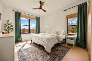 a bedroom with a bed with green curtains and a fan at Villa Acadia with Mountain Views in Bar Harbor