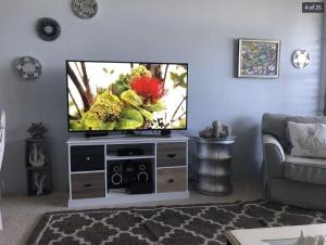 a living room with a flat screen tv on a entertainment center at Oceanfront with Private Beach! Hale Mahina Beach Resort A206 in Lahaina