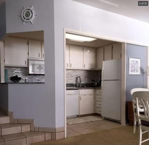 a kitchen with white cabinets and a white refrigerator at Oceanfront with Private Beach! Hale Mahina Beach Resort A206 in Lahaina