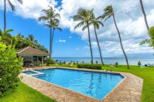 a pool with palm trees and the ocean in the background at Oceanfront with Private Beach! Hale Mahina Beach Resort A206 in Lahaina