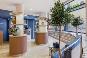 a lobby with a tree and a blue wall at B&B HOTEL Tarragona Centro Urbis in Tarragona