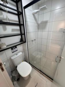 a bathroom with a toilet and a glass shower at Apartamento Moderno uma quadra do mar in Vila Velha
