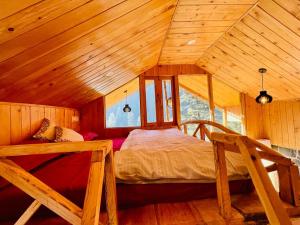 a bedroom with a bed in a wooden attic at Hideaway Tree House in Jibhi