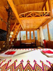 a bedroom with a large bed in a room with windows at Hideaway Tree House in Jibhi