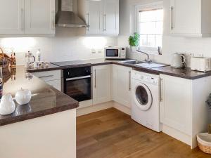 a kitchen with white cabinets and a washer and dryer at Seascape in Garlieston