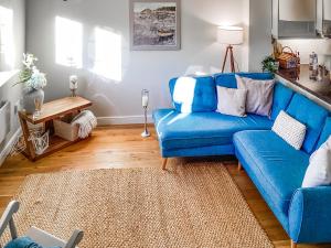 a living room with a blue couch and a table at Seascape in Garlieston