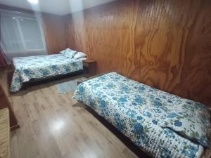 a room with two beds and a wooden wall at Casa Cardenal in Castro +2 photos