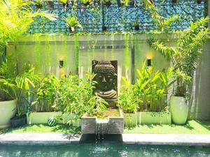 a pool with a statue in a garden with plants at Paddy Villa Sanur in Sanur