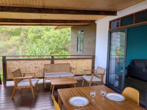 a patio with wooden tables and chairs and a balcony at Mana Henua Lodge in Nuku Hiva