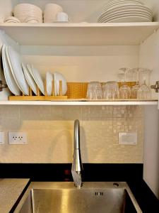 a kitchen sink with plates and dishes on a shelf at Ivory Davao Condotel near DMSF in Davao City