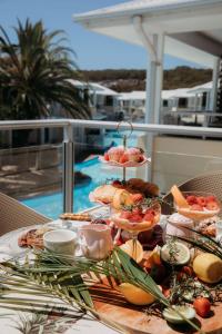 a table with a tray of food on a balcony at Beautifully Restyled Studio Apartment - Oaks Pacific Blue - Sea Salt Escape in Salamander Bay
