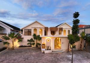 a white house with palm trees in front of it at Casa pumara loft in Kerobokan