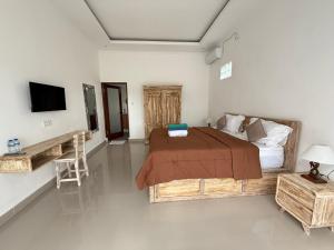 a bedroom with a bed and a television and a table at Puri Lepang Riverside in Ketewel