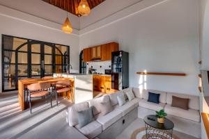 a living room and kitchen with a couch and a table at Tresna Villa Tumbak Bayuh Utara in Dalung