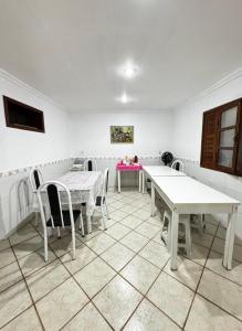 a dining room with white tables and chairs at Casa Marron in Anchieta +12 photos