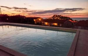 a large swimming pool with a sunset in the background at Bilo Panorama in Castelsardo