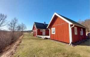 a red house with a black roof on a field at Amazing Home In Slättåkra in Slättåkra +14 photos