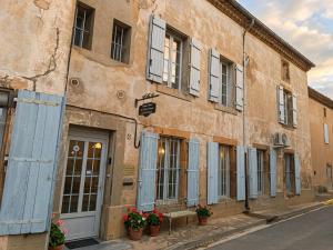 a building with blue doors and windows on a street at Les 2 Drôles d'Oiseaux in Luc-sur-Orbieu