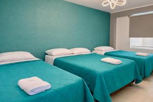 three beds in a room with green walls at LAS GAVIOTAS DE PARACAS in Paracas