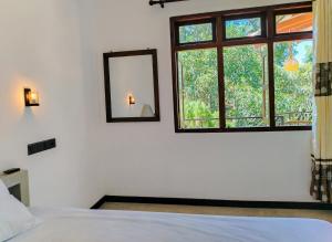 a bedroom with a bed and a mirror and a window at YK House Midigama in Midigama East