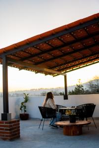 a woman sitting on a patio under a pergola at Montepinar Acosta Suites in Mazamitla +13 photos