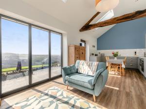 a living room with a blue chair and large windows at Kinder in Mellor