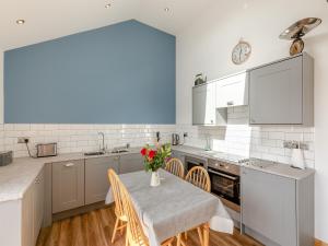 a kitchen with a table with a vase of flowers on it at Kinder in Mellor +24 photos