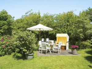 a patio with a table and chairs and an umbrella at Schroeders-Haus-Mitte in Kampen