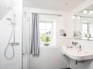 a white bathroom with a shower and a sink at Schroeders-Haus-Mitte in Kampen