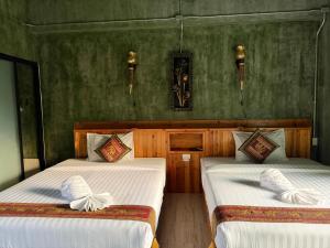 two beds in a room with green walls at Keeree at chiewlarn in Ban Tha Khun