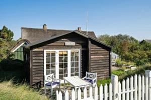a small cabin with two chairs and a fence at Charming Tiny House In Sønderho in Fanø