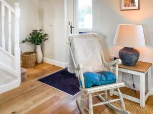 a white rocking chair next to a table with a lamp at Seascape in Garlieston