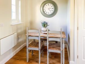 a dining room table with two chairs and a clock on the wall at Seascape in Garlieston +9 photos