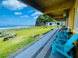 a porch with blue chairs and a view of the ocean at Lanyu IGANG Hotel in Lanyu