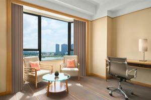 a room with a chair and a desk and a table at Renaissance Riverside Hotel Saigon in Ho Chi Minh City